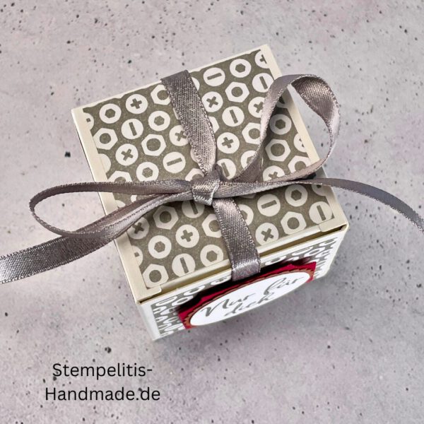 handdekorierte Geschenkschachtel mit Aufschrift „Nur für dich“, Geschenkschachtel mit grauem Muster und rotem Etikett, kleine Geschenkbox mit Satinband, Vorderansicht der Schachtel „Nur für dich“, offene Geschenkbox mit Inhalt, Detailaufnahme Schriftzug „Nur für dich“, stilvolle Geschenkverpackung mit Band